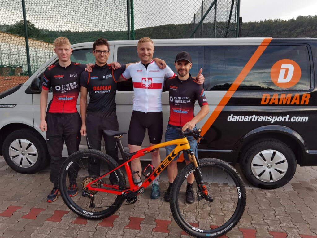 Drużyna Damar Cycling Team MTB w strojach kolarskich przed samochodem firmowym Damar Transport